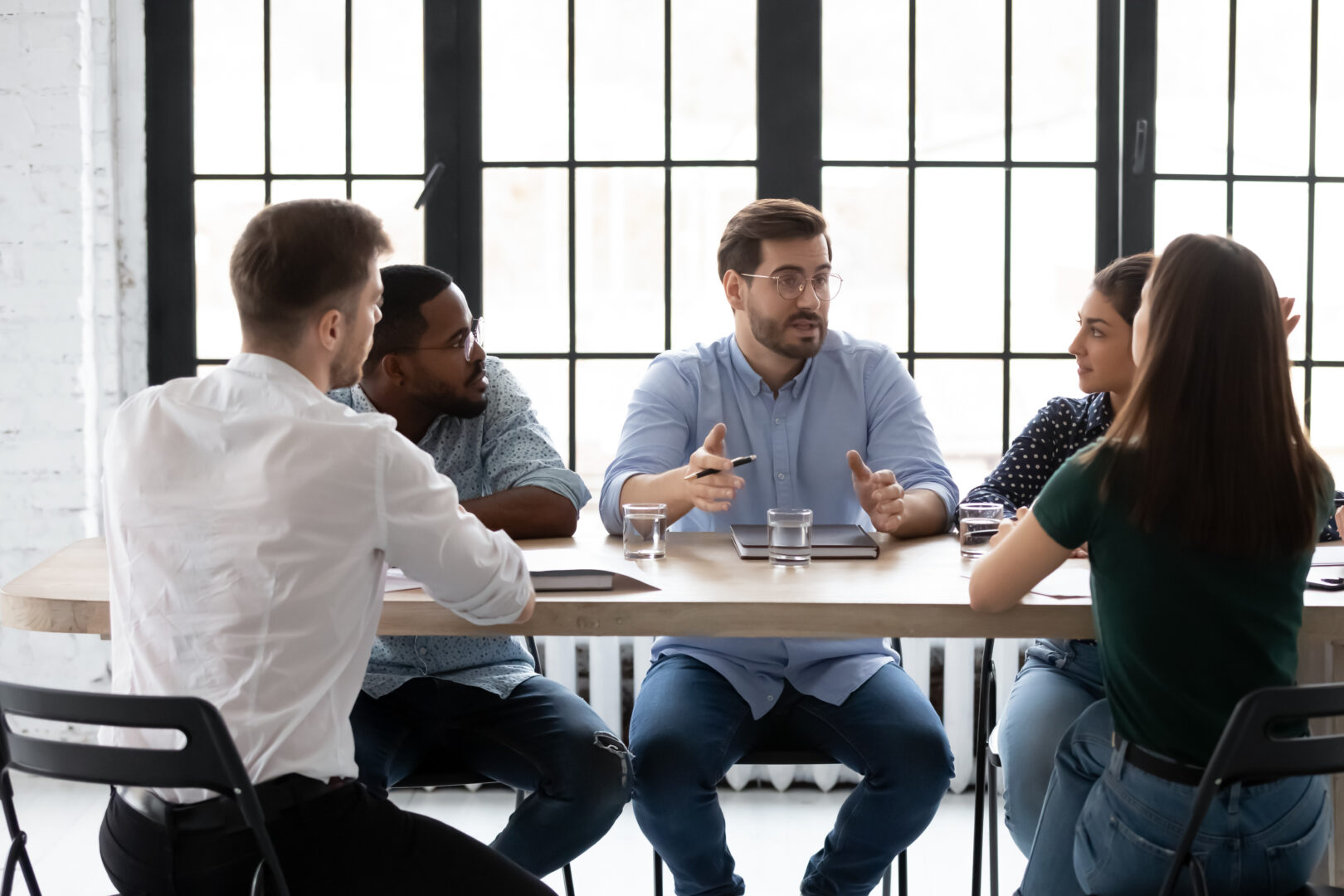 Business team of five millennial members brainstorming at office boardroom