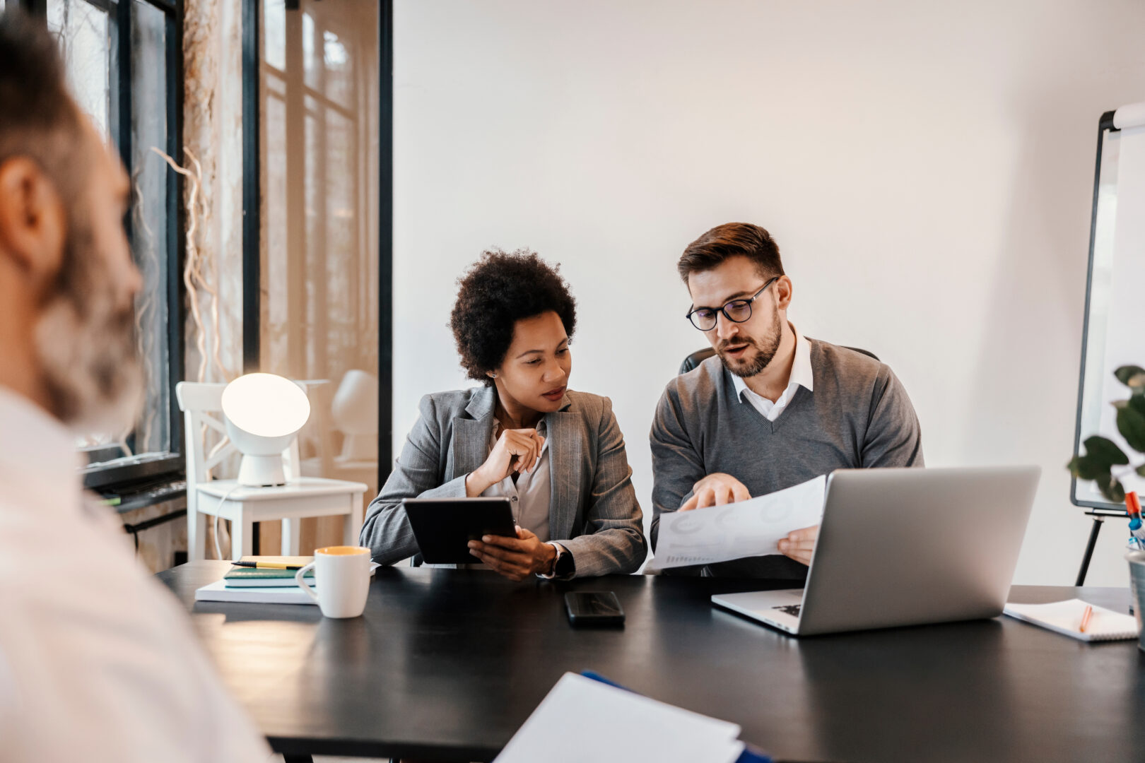 A multicultural executives are sitting at the corporate firm at the office and looking at the paperwork and solution about project.
